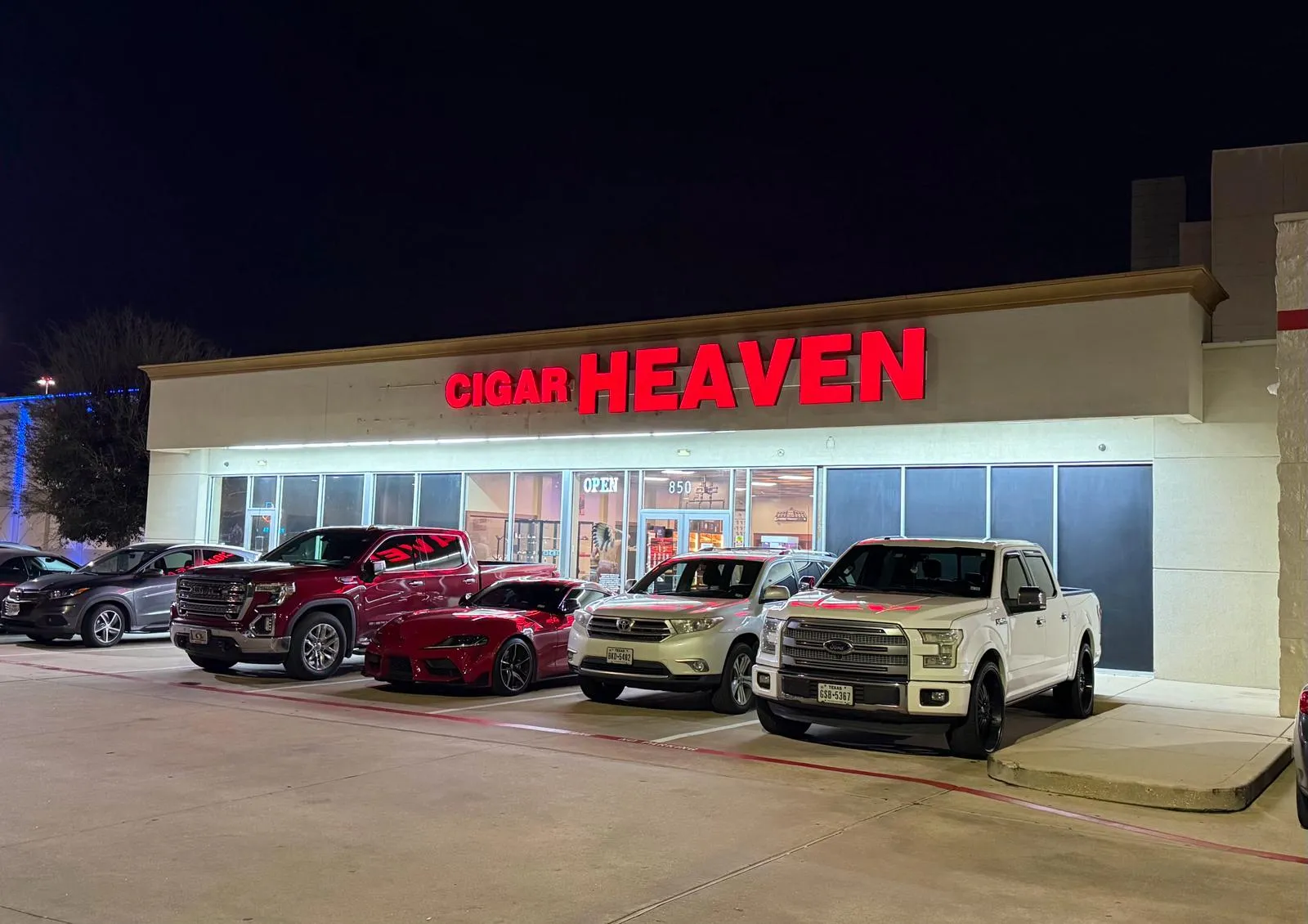 Cigar Heaven storefront at night — the red CIGAR HEAVEN sign above the entrance at 850 Kobayashi Rd S, Webster, TX. Open until late.