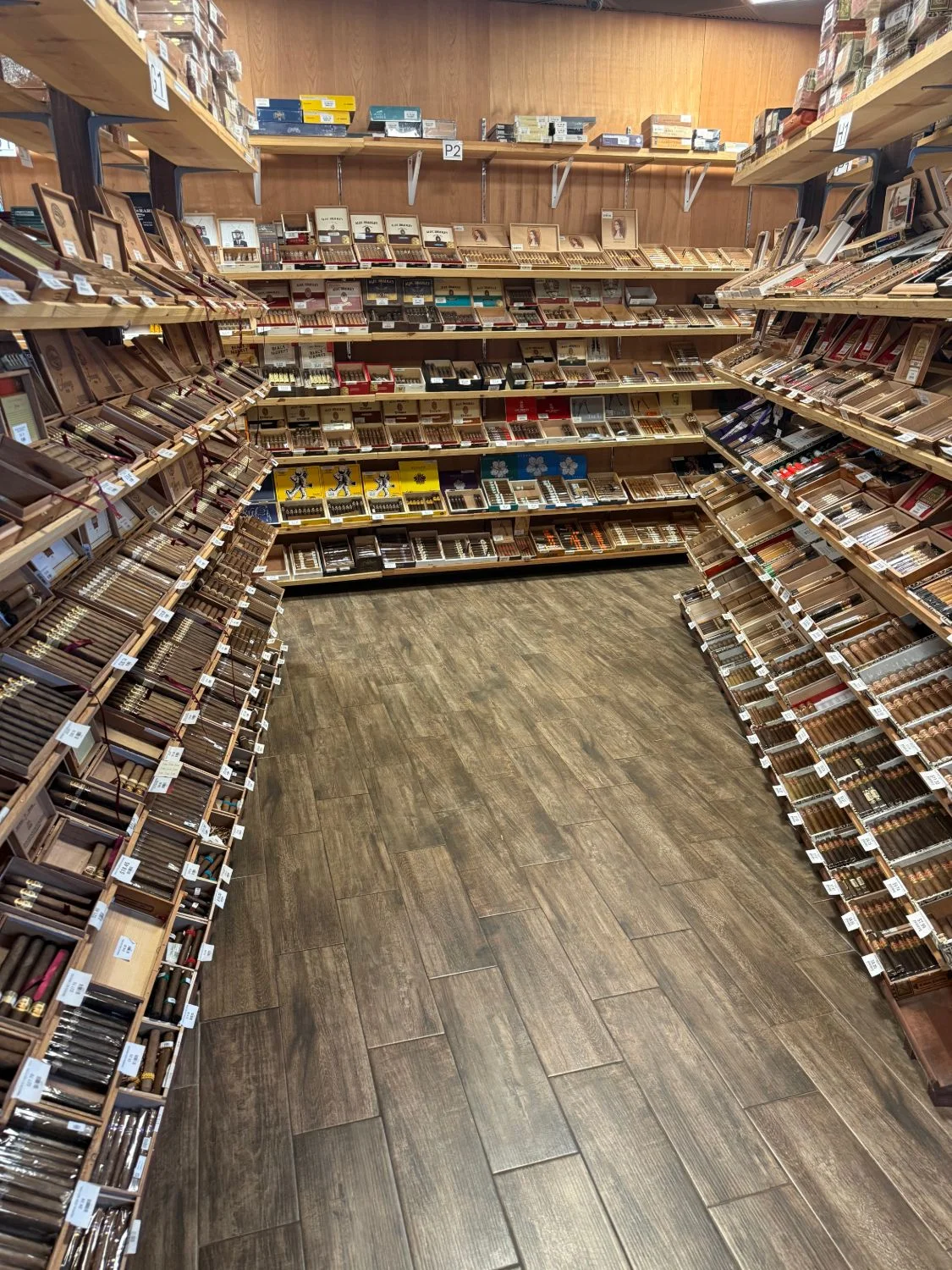 A U-shaped bay in the Cigar Heaven humidor — three walls of angled shelves lined with open cigar boxes.
