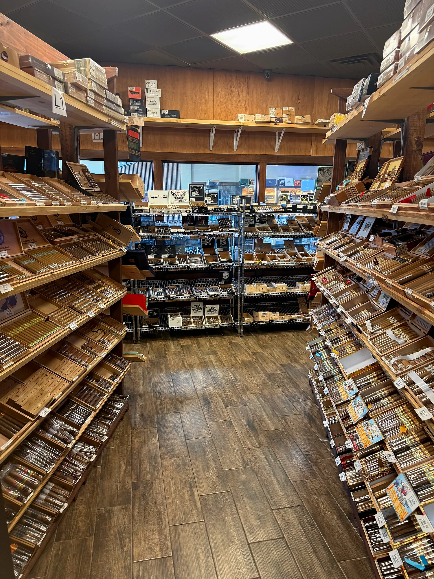 A boutique aisle in the Cigar Heaven humidor — angled shelves on both sides and wire racks along the windows.