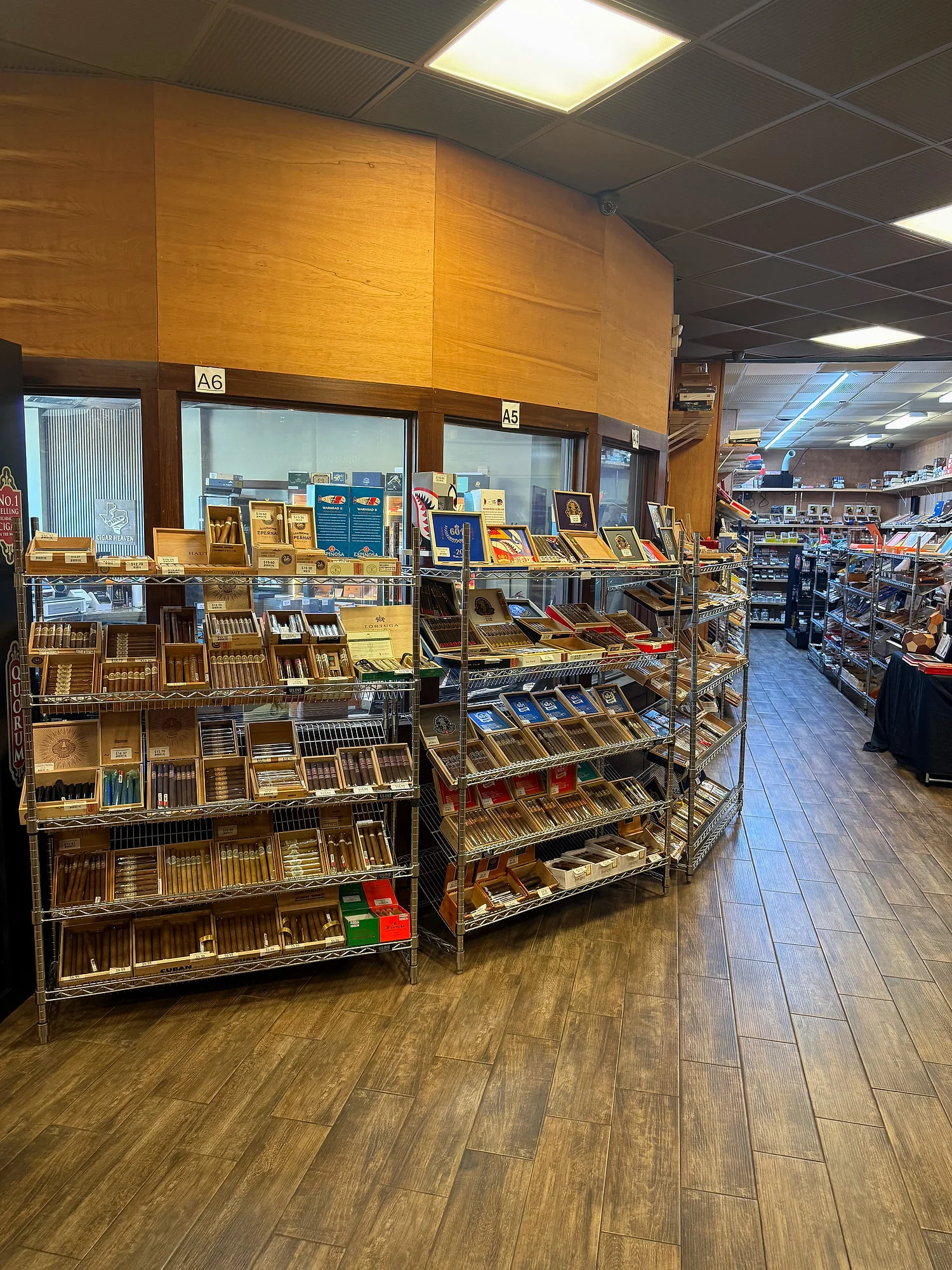 Wire racks with Espinosa and other boutique boxes by the humidor windows at Cigar Heaven.