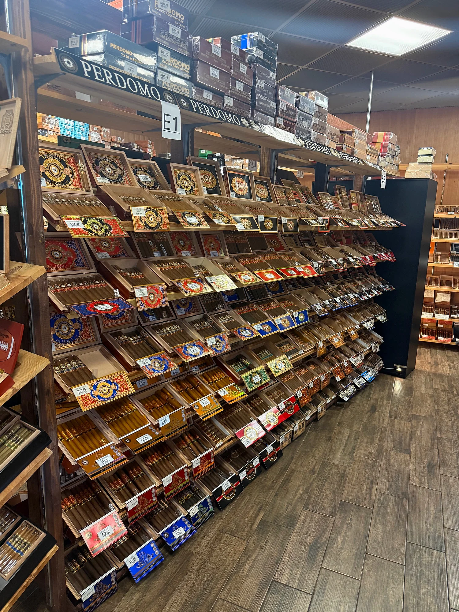 The Perdomo wall in the Cigar Heaven humidor — rows of open Perdomo boxes on angled shelves.