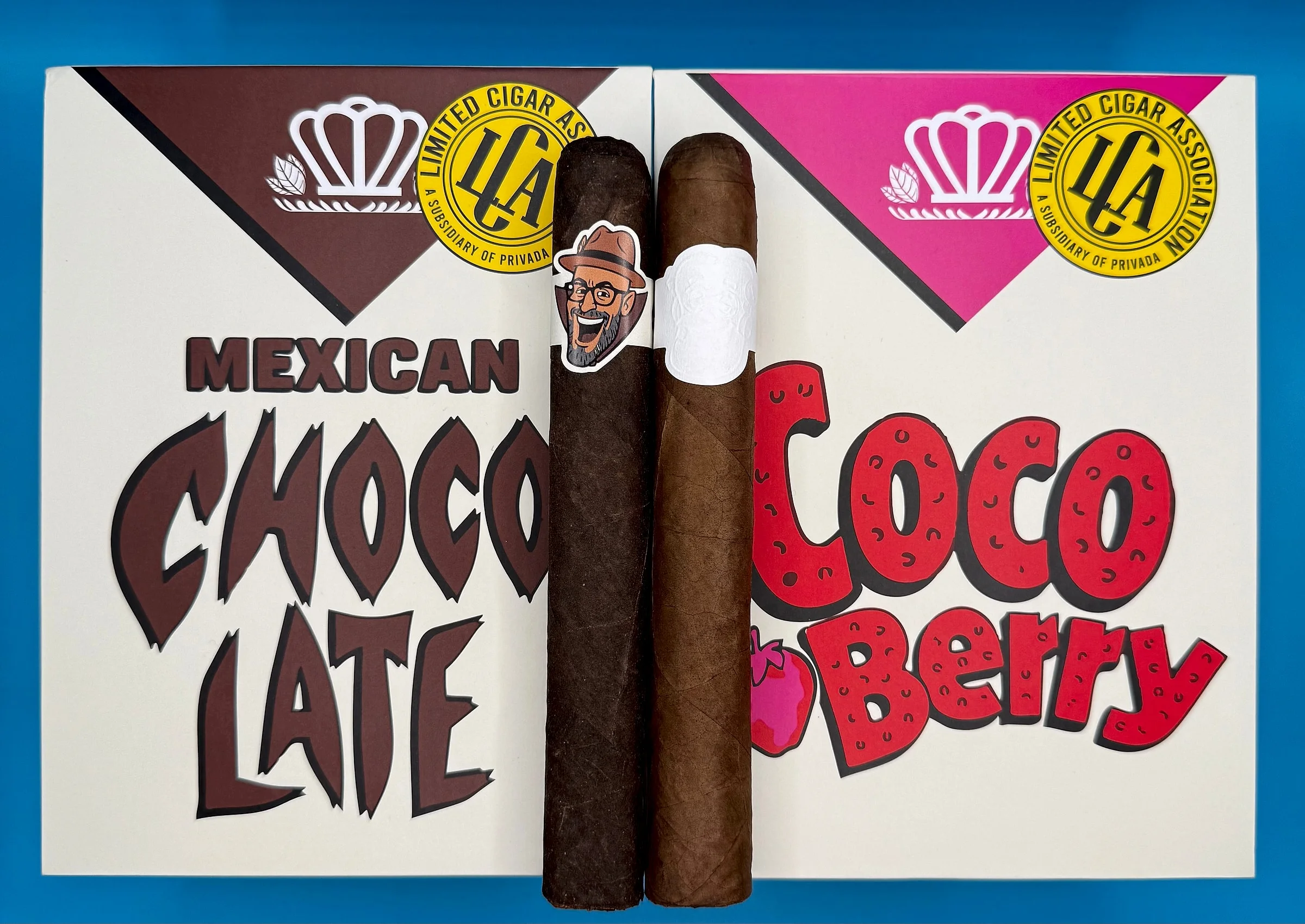 Two LCA cigars, one with a cartoon band and one with a plain white band, laid over Mexican Chocolate and Coco Berry boxes from the Limited Cigar Association.