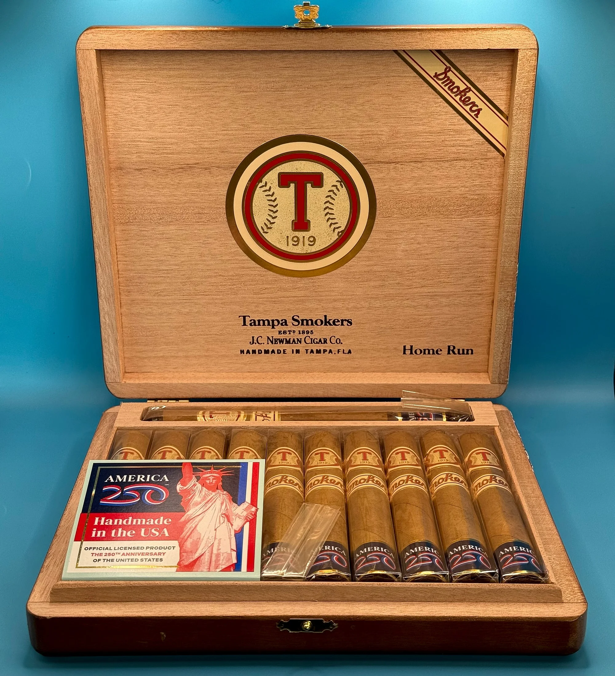 An open box of J.C. Newman Tampa Smokers Home Run cigars with America 250 bands, handmade in Tampa, Florida.