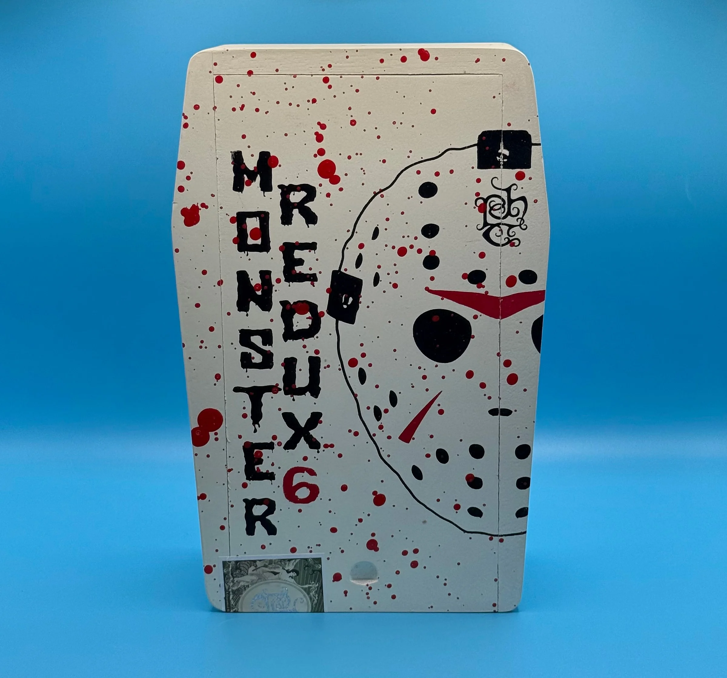 The Tatuaje Monster Series The Jason Redux 6 coffin box, painted white with a hockey-mask drawing and red splatter.